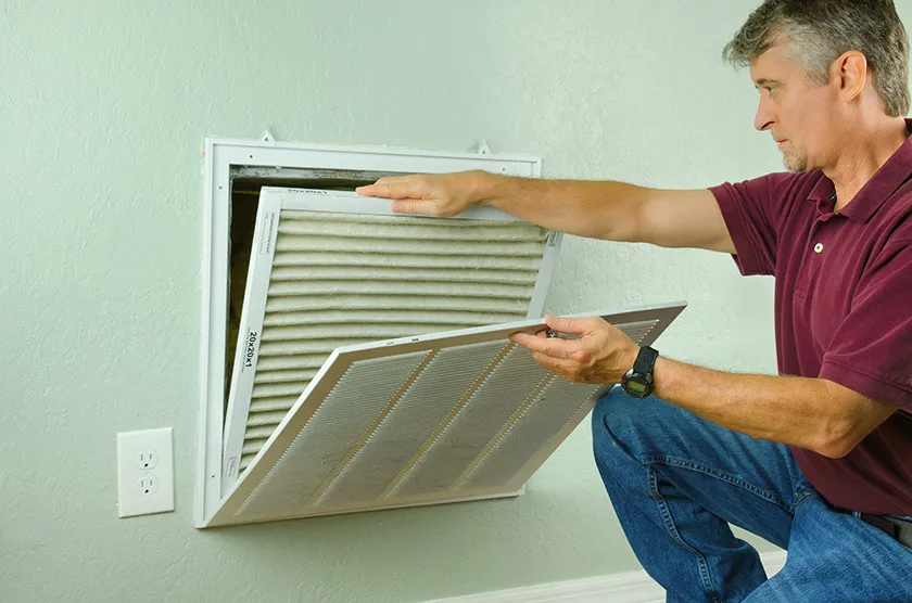 Person changing the dirty filter of a home air vent
