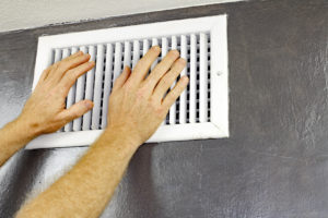 checking an HVAC vent on a wall